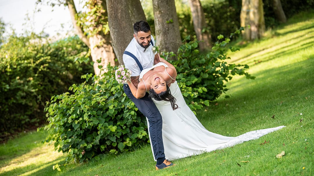 Bride tilts back laughing with groom